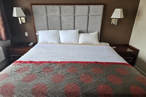 A hotel room with a large bed, two bedside tables, a telephone, and wall-mounted lamps.