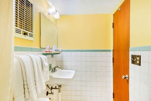 Ein Badezimmer mit Waschbecken, Spiegel, Handtuchhalter und einer Tür.