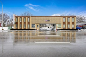Ein Motel mit einer zentralen Eingangspforte, zahlreichen Fenstern und einem Parkplatz mit Schnee.
