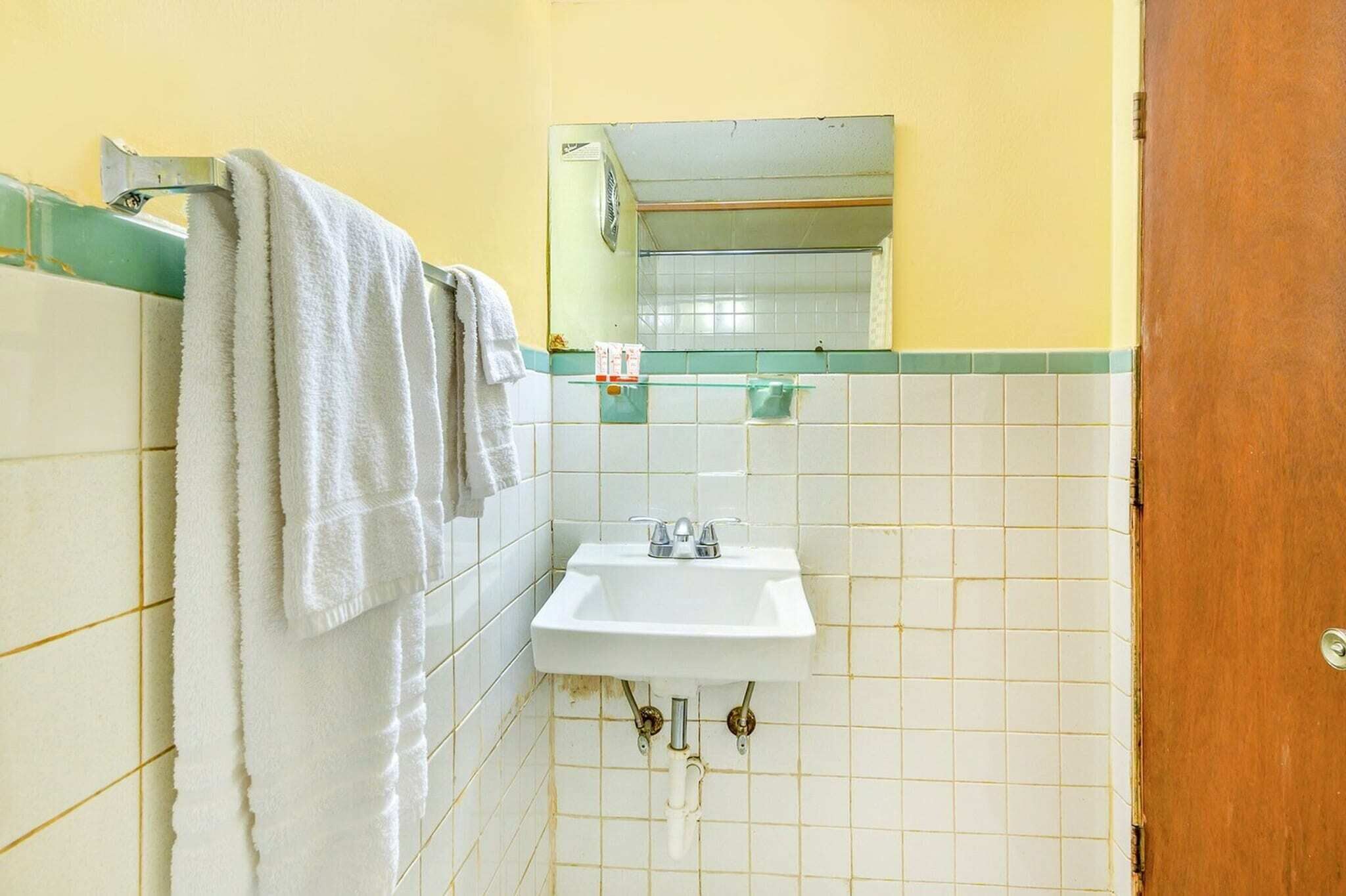 A bathroom with a white sink, a mirror above it, and a towel rack with towels.