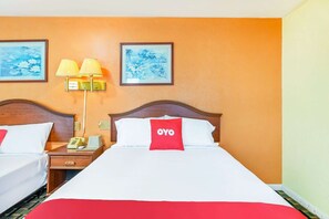 Habitación de hotel con dos camas, una mesita de noche con teléfono y dos lámparas de pared.