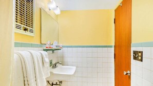 Un baño con lavamanos, espejo, toallero y una puerta.