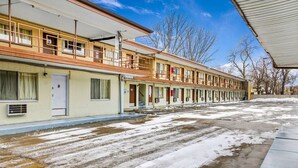 Un motel con una fila de habitaciones, un corredor cubierto y el suelo cubierto de nieve.