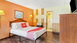 Una habitación de hotel con cama, televisión, escritorio y puerta.