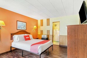 A hotel room with a bed, a TV, a desk, and a door.