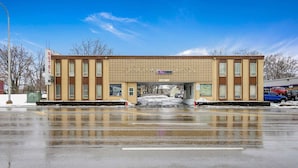Un motel avec une entrée principale, de nombreuses fenêtres et un parking enneigé.