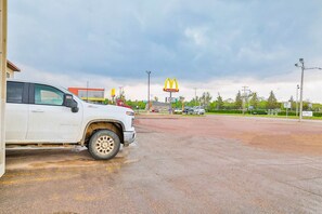 Un estacionamiento con una camioneta blanca, un letrero de McDonald's y un edificio al fondo.