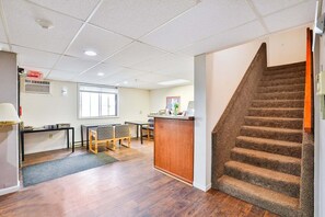 Un espace d’accueil comprenant un bureau, des chaises, un petit comptoir et un escalier.
