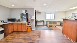 A kitchen with wooden cabinets, a microwave, a coffee machine, and a small table with chairs. - Pipestone|Queen Bed|Nsmk (Pipestone)