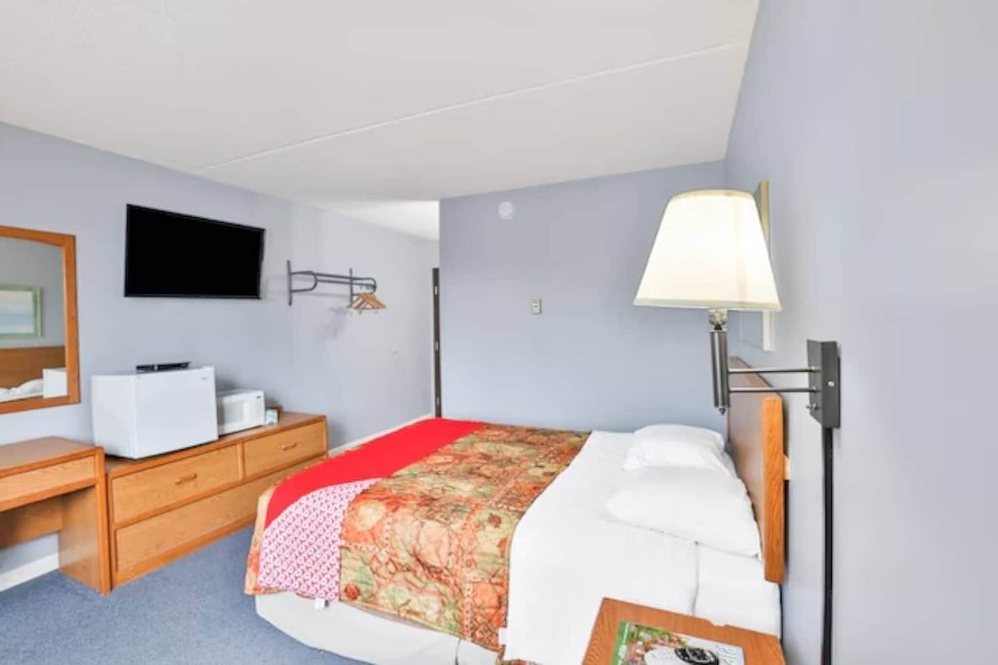 Ein Schlafzimmer mit einem Bett, einem Schreibtisch, einem Stuhl, einem Fernseher und einer Lampe.