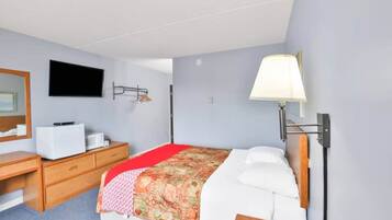 Ein Schlafzimmer mit einem Bett, einem Schreibtisch, einem Stuhl, einem Fernseher und einer Lampe.