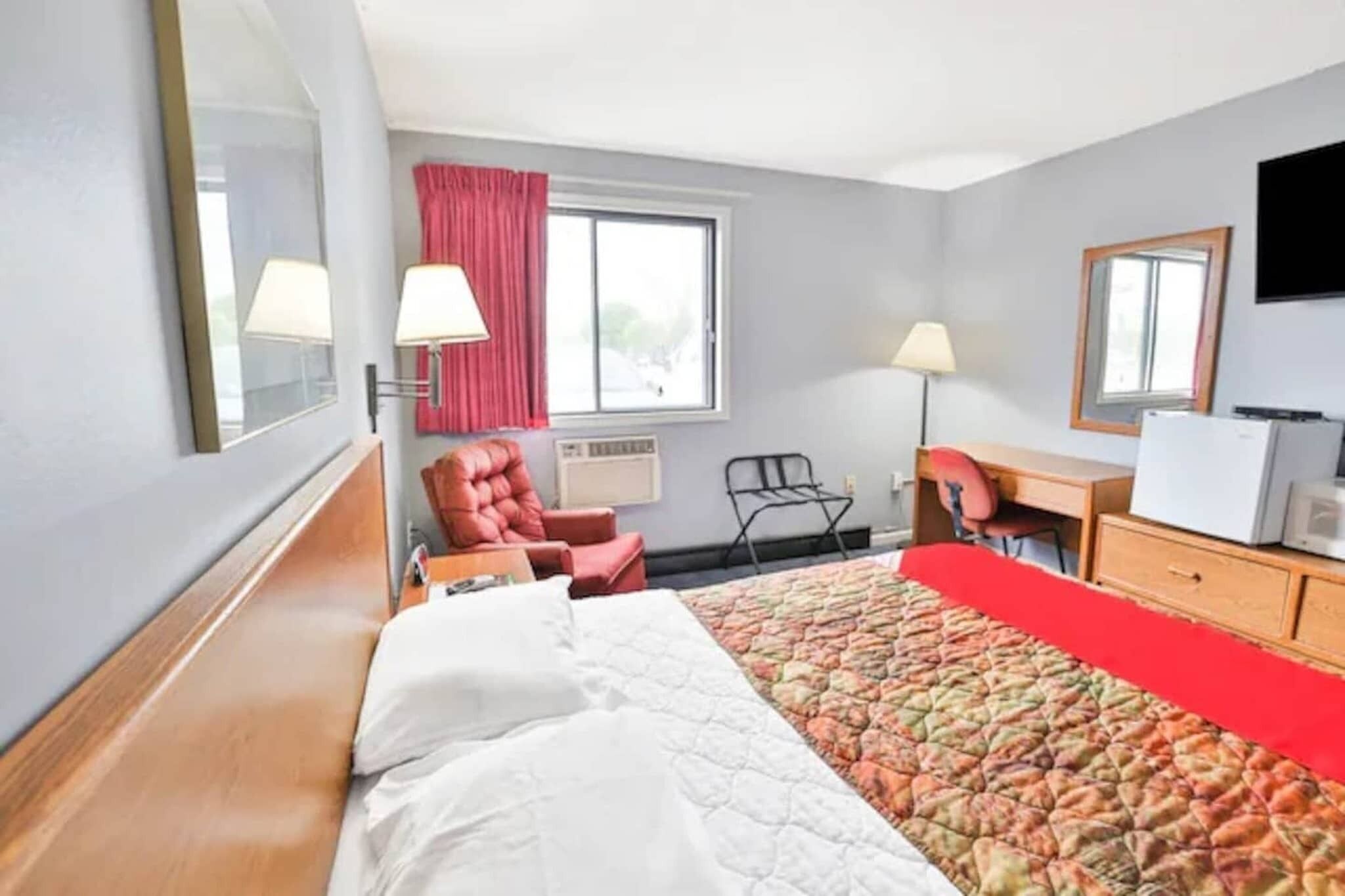 Hotellihuone, jossa on sänky, työpöytä, tuoli, televisio ja ikkuna.