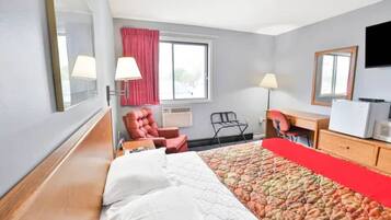 Hotellihuone, jossa on sänky, työpöytä, tuoli, televisio ja ikkuna.