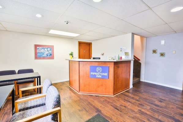 A hotel lobby with a reception desk, a dining area with a table and chairs, and a staircase. - Pipestone|Queen Bed|Nsmk (Pipestone)