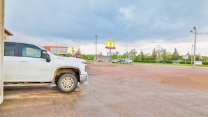 A parking lot with a white truck, a McDonald's sign, and a building in the background. - Pipestone|Queen Bed|Nsmk (Pipestone)