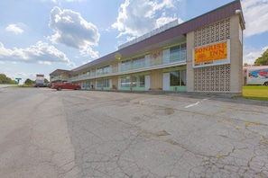 A motel with a balcony on the second floor, a sign for Sunrise Inn, and a truck parked outside.