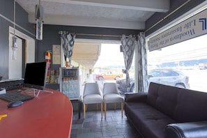 Ein Empfangsbereich mit Schreibtisch, Computer, Stühlen und einer Couch, mit Blick ins Freie.