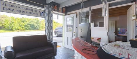 A room with a sofa, a desk with a computer, and a bed.