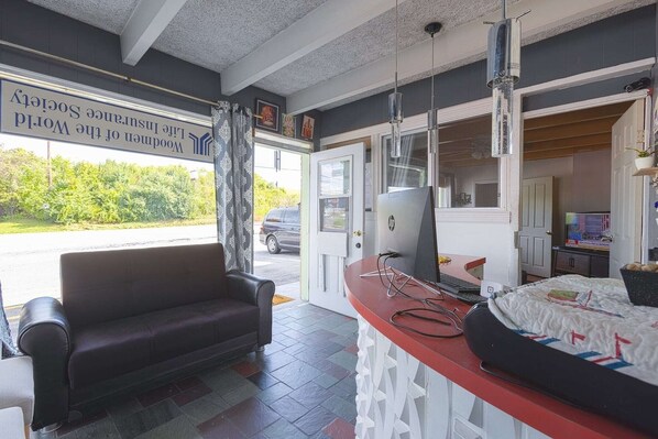 A room with a sofa, a desk with a computer, and a bed.