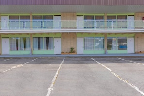 A two-story motel with numbered rooms, a parking lot, and a small garden area.