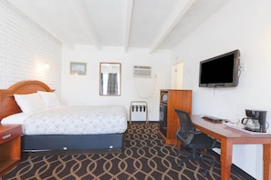 Ein Hotelzimmer mit Bett, Schreibtisch, Stuhl, Fernseher und einer Kaffeemaschine.