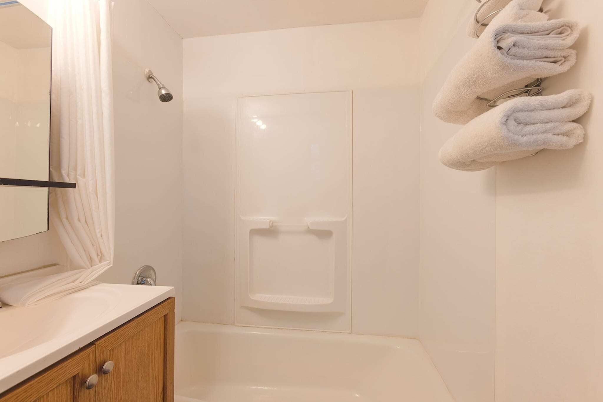 Un baño con ducha, lavabo y toallero.