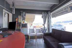 Un espace d’accueil comprenant un bureau, un ordinateur, des chaises, un canapé et une vue sur l’extérieur.