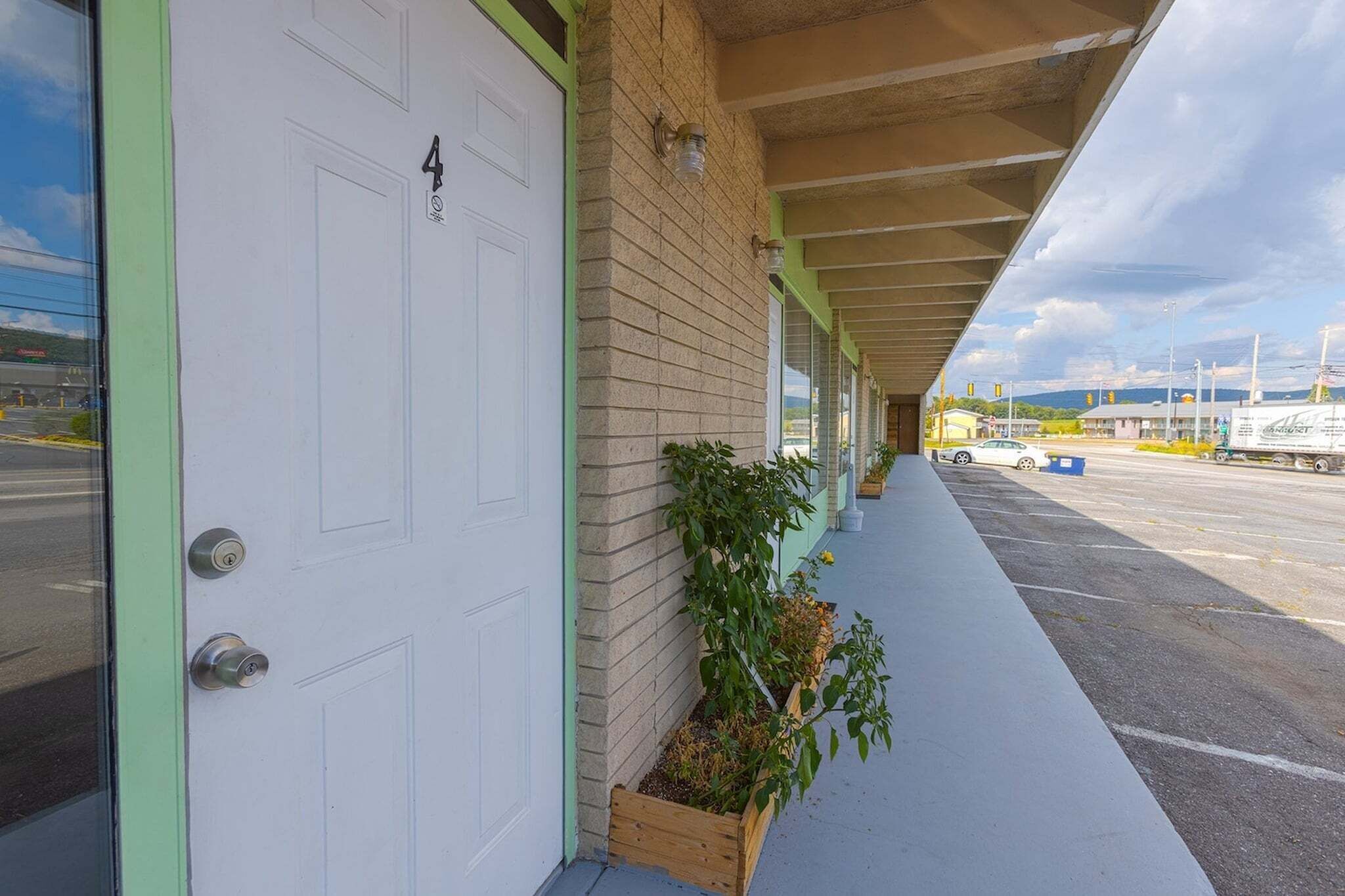 A building with a white door, a brick wall, and a covered walkway.