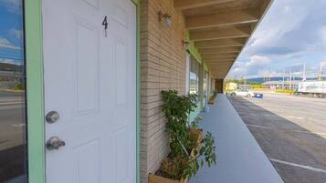 A building with a white door, a brick wall, and a covered walkway.