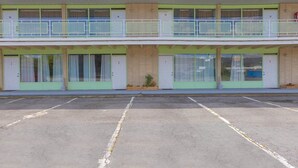 A two-story motel with numbered rooms, a parking lot, and a small garden area.