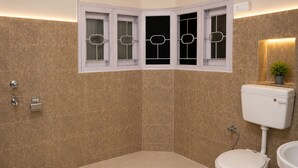 A bathroom with a toilet, bidet, and a window with a plant. - Jannat Hotel - Solan (Solan)