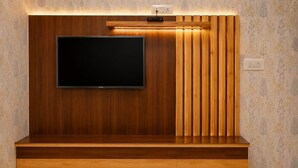 A modern entertainment unit with a flat-screen TV, wooden paneling, and integrated lighting. - Jannat Hotel - Solan (Solan)