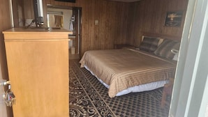 A bedroom with a bed, a wooden desk, a computer, and a patterned rug. - King Bed|Non-Smoking (Quinter)