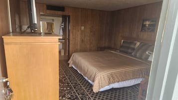 Ein Schlafzimmer mit einem Bett, einem Holztisch, einem Computer und einem gemusterten Teppich.