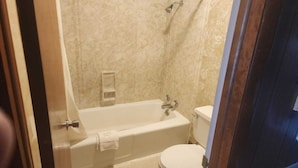 A bathroom with a bathtub, toilet, and shower area. - King Bed|Non-Smoking (Quinter)