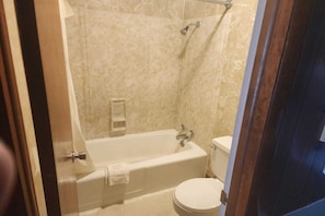 A bathroom with a bathtub, toilet, and shower area.