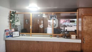 A reception desk with a 'OPEN' sign, a 'KEY DROP' box, a 'Take One' sign, and a 'MOVING GUY' box. - King Bed|Non-Smoking (Quinter)