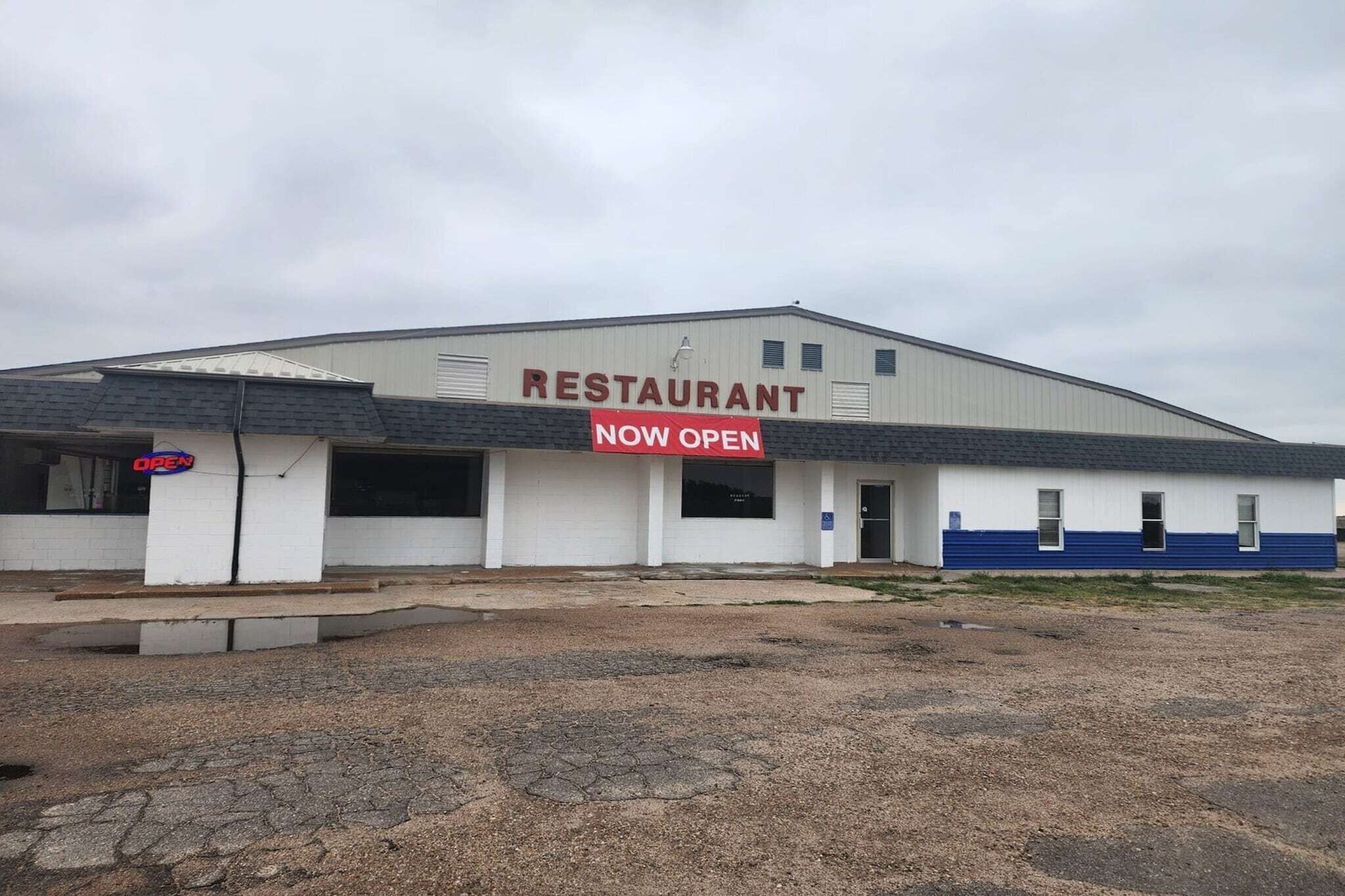 A restaurant building with a 'NOW OPEN' sign.