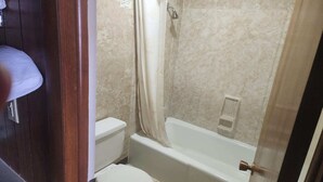 Et badeværelse med toilet, badekar og bruseforhæng.