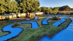Un jardín laberinto con senderos serpenteantes y fuentes de agua con azulejos azules.