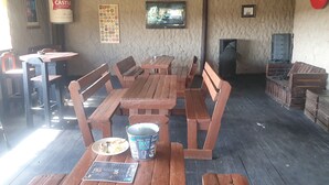 Un comedor rústico con bancos y mesas de madera, una lata de cerveza, un plato con restos de comida y una chimenea.