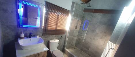 A bathroom with a white sink, toilet, and shower.