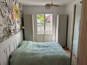 Ein Schlafzimmer mit Bett, Kleiderschrank und Blick durch eine Tür.