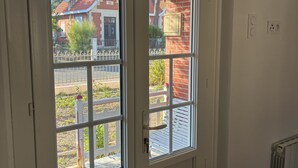 A room with a white door, a radiator, and a view of a brick house with a red roof. - A home in Soulac, just a stone's throw from downtown and the beach (Soulac-sur-Mer)