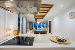 Una cocina moderna con placa de inducción, una zona de comedor con mesa y sillas de madera, y vistas al exterior.