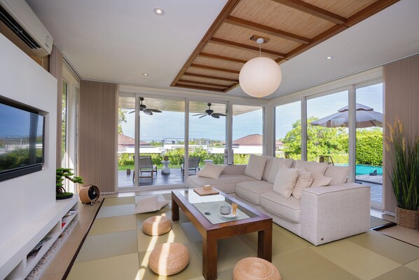 Una sala de estar moderna con sofá, mesa de centro y ventanas amplias.