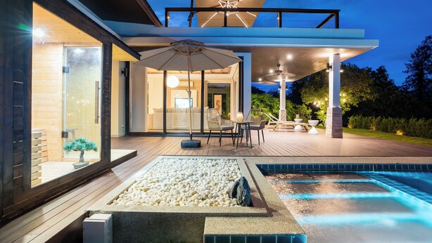 Una casa moderna amb piscina, zona d'estar exterior i un porxo cobert.
