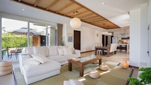 Un saló modern amb un sofà, una taula de centre, esteves de tatami i una zona de menjador amb cadires.