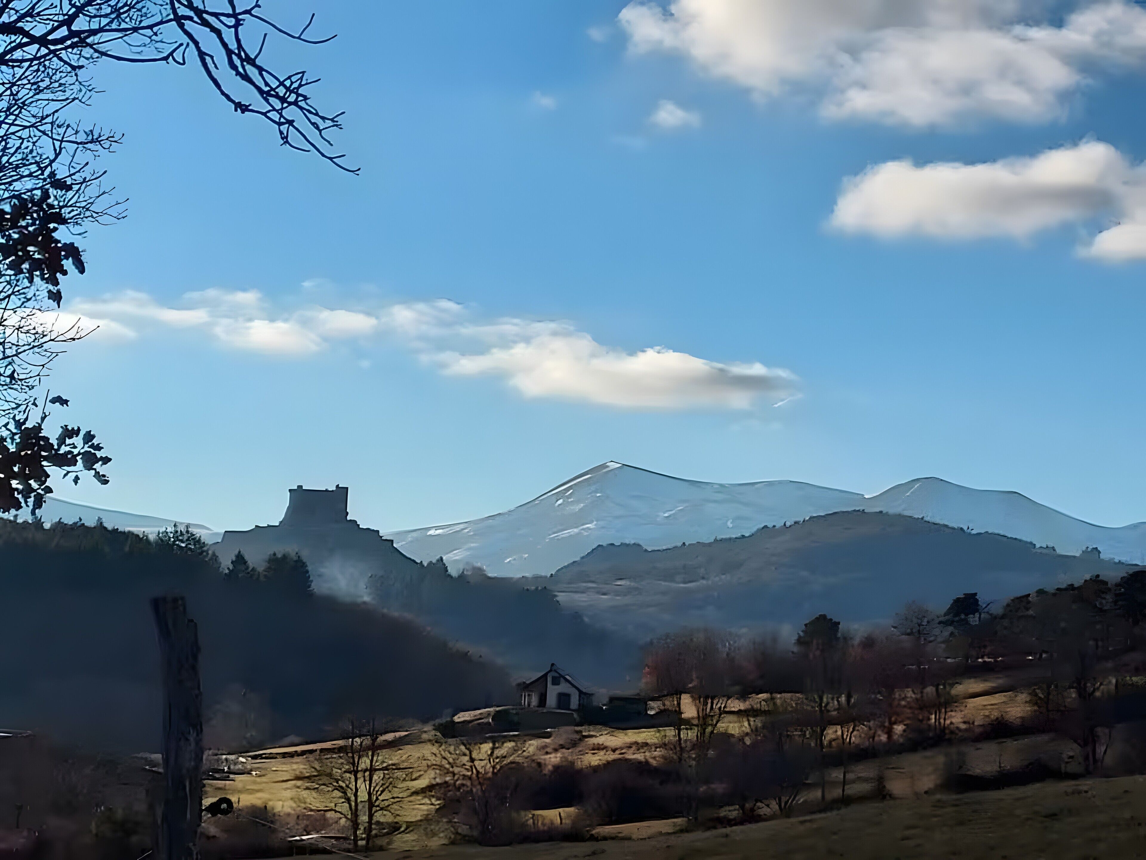A mountainous landscape with a castle-like structure, a small house, and a clear sky.