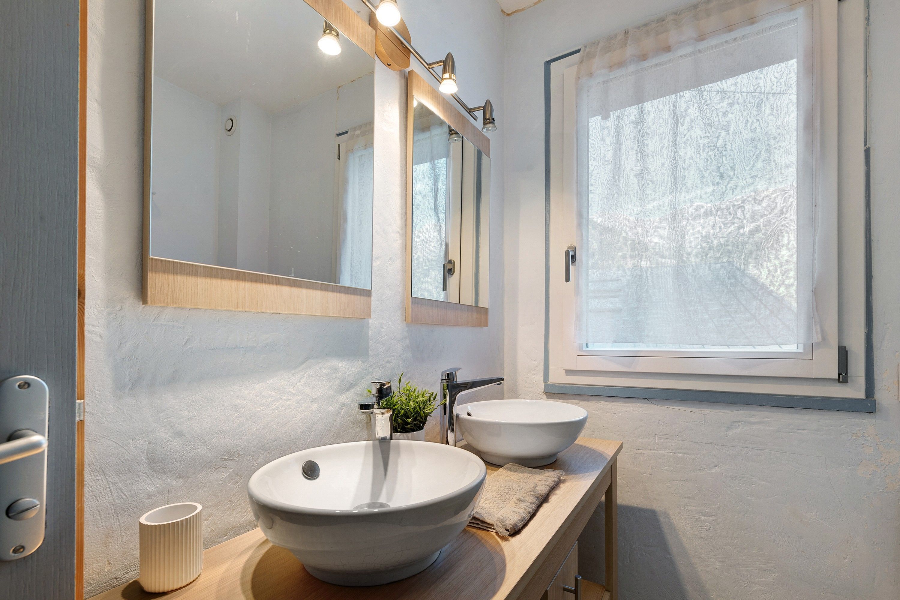 Een badkamer met een grote spiegel, twee wasbakken, een handdoek en een raam.